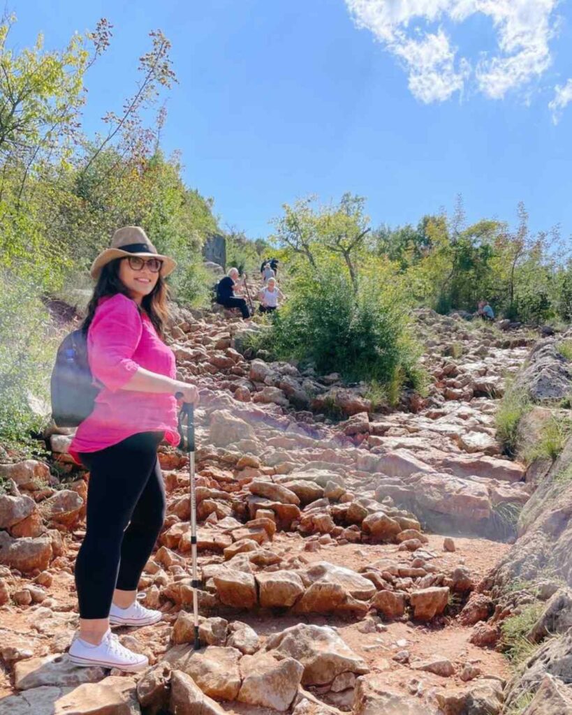 A woman walking up Apparition Hill with a walking stick.