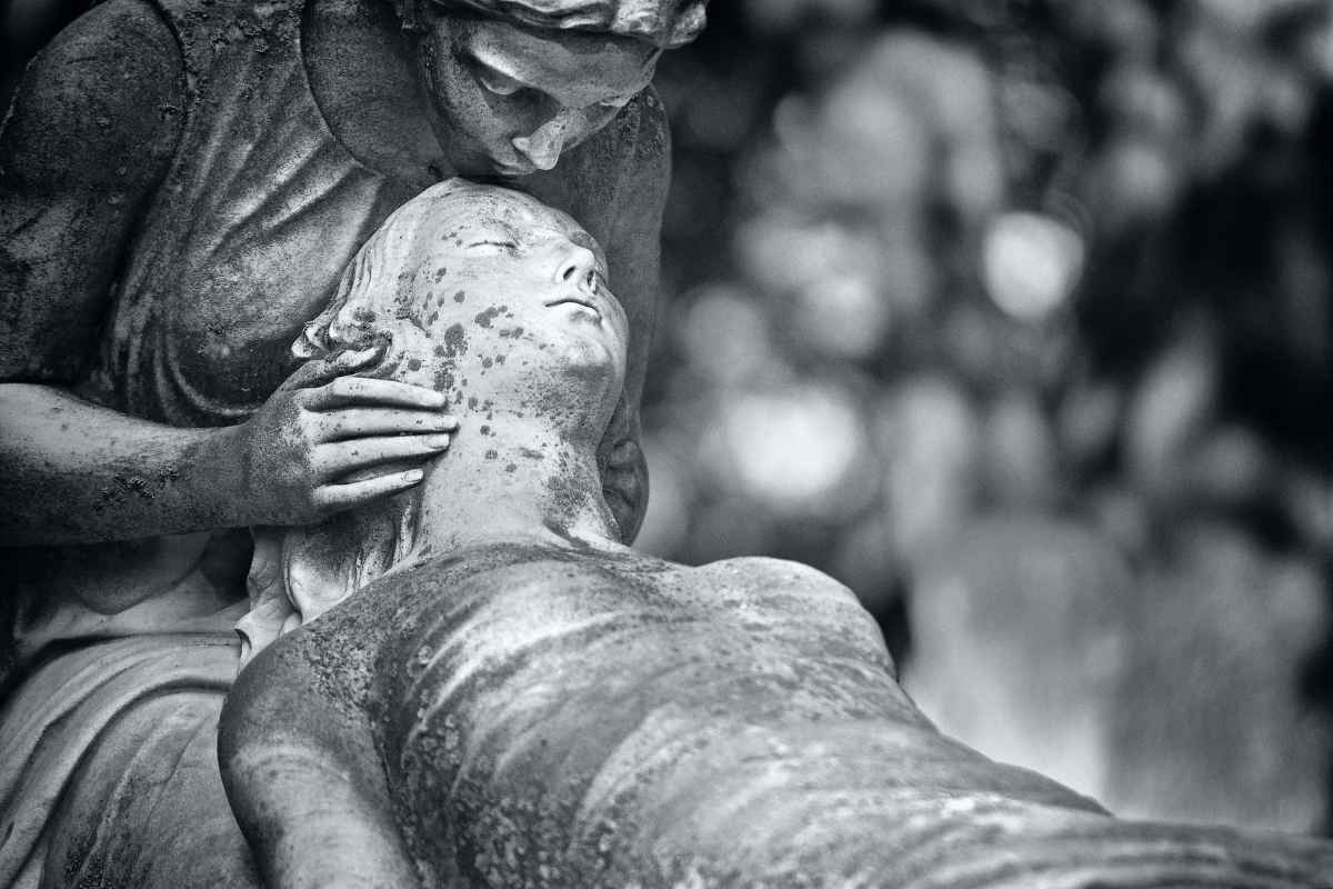 A statue of two women, one holding the other. Comforting spiritual life coaching atmosphere.