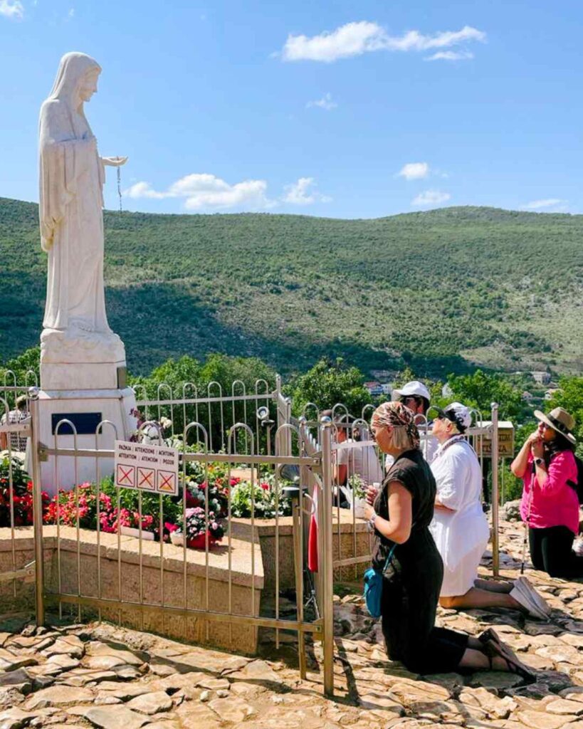 Praying in front of the statue of the Virgen Mary in Medjugorje