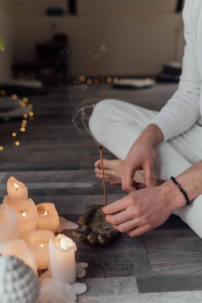 A woman sitting on the floor during a spiritual life coaching session lighting incense.