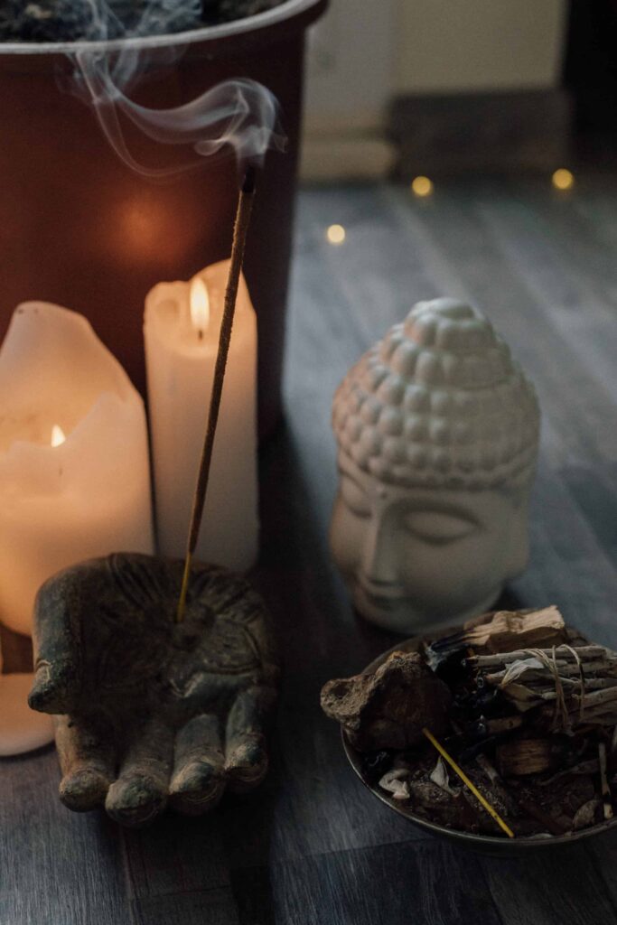 Items a spiritual life coach might use in a coaching session: candles, incense, sage, and a statue of Buddha.
