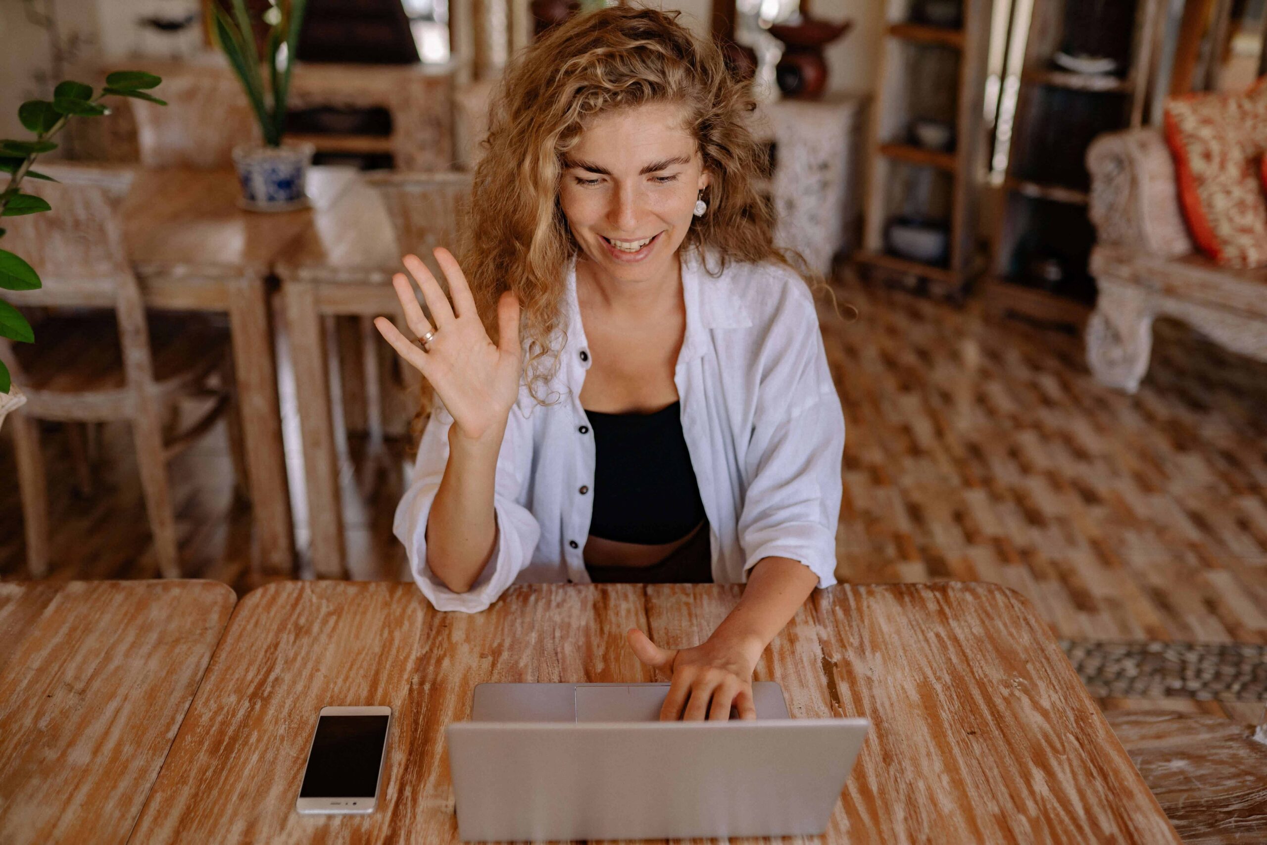 Life coach for women waving to her client during an online session.